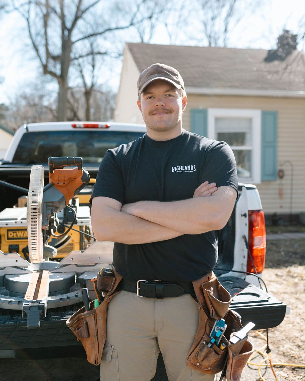 Adam Ginn standing with folded arms beside his jobsite tools